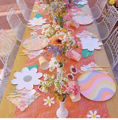 a long table with flowers and paper plates on it