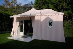 a pink and white tent sitting on top of a lush green field