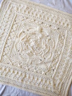 a white crocheted blanket sitting on top of a bed