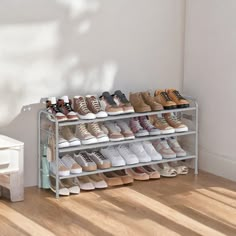 there is a rack with many pairs of shoes on it in front of a white wall