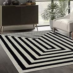 a black and white rug in a living room next to a chair with a plant on it