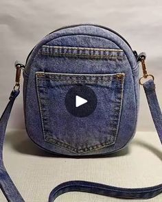 a blue jean purse with a white button on the front pocket and a strap around it