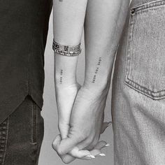 two people holding hands with tattoos on their arms and the words love are written on them