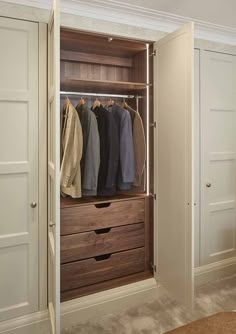 an open closet with clothes hanging on the rails and two drawers in front of it