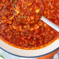 a spoon in a bowl filled with chili and carrots