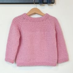 a pink sweater hanging on a clothes hanger