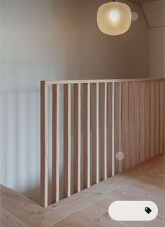 an empty room with wooden slats on the floor and a round light fixture hanging from the ceiling