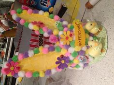 a cake decorated like a banana with flowers and rubber ducks on the top, sitting on a table