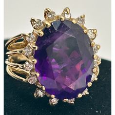 This is part of Chairish’s Fine Jewelry assortment.  14k yellow gold cocktail ring featuring a deep purple/red/blue oval amethyst, encircled by 16 small diamonds.  Ring Size: 6 in. Stone: 16.42 x 12.40 x 8.7 mm Ring Weight: 6.7 grams  If you would like more information, please contact me via email, mrboult@gmail.com. Oval Amethyst Ring In Halo Setting Yellow Gold, Oval Yellow Gold Amethyst Ring With Halo Setting, Oval Amethyst Ring In Yellow Gold With Halo Setting, Luxury Oval Amethyst Ring With Diamond Accents, Oval Diamond Ring With Gemstone Accents For Formal Occasions, Purple Oval Diamond Ring, Oval Amethyst Ring With Gemstone Accents For Formal Occasions, Oval Purple Diamond Ring With Gemstone Accents, Oval Purple Diamond Ring