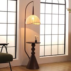 a floor lamp sitting on top of a table next to a window