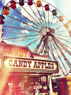 an old photo of a candy apples stand with a ferris wheel in the back ground