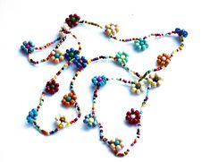 "Add colorful floral fun to your outfits with this charming necklace featuring hand-beaded flowers all along its generous 24\" length! Vibrant multicolored beads form little flowers and add delicate, yet eye-grabbing style as they dangle! And perhaps buy a couple chains at a discount to double the floral loveliness! And consider a coordinating ankle bracelet, pictured above to complete your set! Beaded Flower Necklace (elasticized cord), 24\" long, flowers 1/2\" diameter MANY ARTFUL ITEMS ARE AV Colorful Beaded Flower Necklace For The Beach, Colorful Beaded Flower Necklace For Beach, Summer Beaded Flower-shaped Jewelry, Bohemian Multicolor Necklaces With Flower Charm, Spring Bohemian Jewelry With Colorful Beads, Bohemian Multicolor Necklace With Flower Charm, Bohemian Spring Jewelry With Colorful Beads, Bohemian Flower Necklace With Round Beads For Beach, Multicolor Flower Necklace As Spring Gift