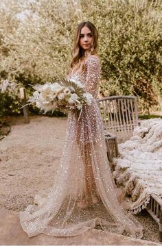 a woman in a wedding dress standing next to a bench with flowers and greenery