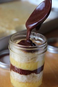 a spoon is pouring chocolate into a jar