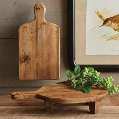 a bird sitting on top of a wooden table next to a cutting board and grapes