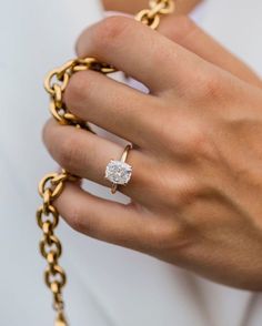 a close up of a person's hand with a gold chain ring and diamond