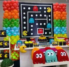 a table with balloons and decorations for a pacman themed birthday party on it's wall