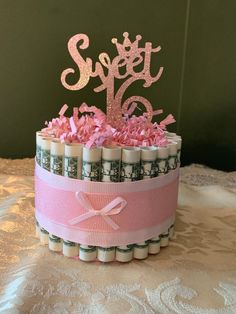 a birthday cake made out of rolled money and pink frosting with the word sweet sixteen on top