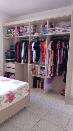 a bedroom with a bed, closet and clothes on shelves