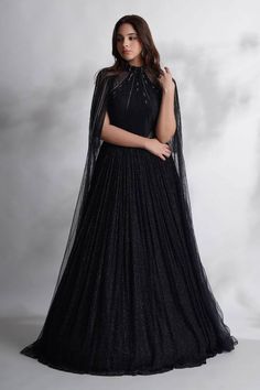 Black sheer cape featuring cutdana, stones and sequin embellished stripe patterns. Comes with cut-out padded gown in a textured patterned base, nalki embroidery and attached can can. - Aza Fashions Elegant Cape Gown For Festive Occasions, Elegant Cape Gown For Festive Season, Elegant Festive Cape Gown, Cape-shape Embellished Dress For Reception, Embellished Cape Dress For Reception, Embellished Gown With Cape Sleeves, Embellished Evening Dress With Cape Sleeves For Reception, Festive Evening Dress With Sequins And Cape Sleeves, Embellished Gown With Cape Sleeves For Gala