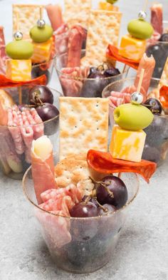 crackers, grapes and cheese are arranged in cups