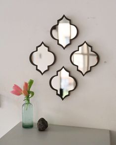 three mirrors on the wall above a vase with flowers