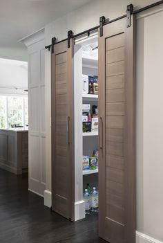 an open pantry with sliding doors in a kitchen next to a hardwood floor and white walls