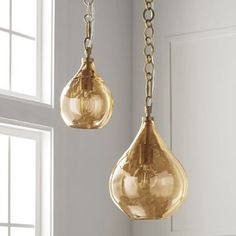 two gold colored glass pendants hanging from a window sill in a white room