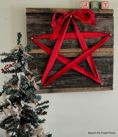 a wooden star with red ribbon tied around it on top of a sign that says joy