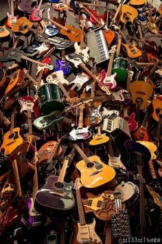 a large pile of guitars and electric guitars