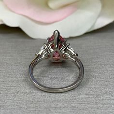 "This ring is a pear shape pink simulated diamond with trillion sides, 14k white gold #6274 Rose Gold is available upon request as a custom order and is a final sale (non refundable, non returnable, non exchangeable) -Approximate total carat weight: 4.90ctw diamond equivalent -Center Stone Size: approx. 4.10ct diamond equivalent -Gem Type: simulated diamond -Stone Shape: pear shape 13x9mm -Stone Clarity: VVS1 -Stone Color: pink -Moh's Scale: 8.5 Hardness -Accent Stones: 2 trillions -Stone size: Pink Engagement, Engagement Ring Pear, Pink Engagement Ring, 3 Stone Ring, Pear Shaped Engagement Rings, Princess Ring, Cz Rings Engagement, 3 Stone Rings, White Gold Set