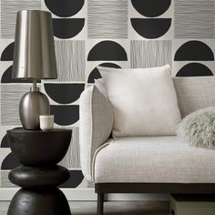 a living room with black and white wallpaper, a chair and lamp on the floor