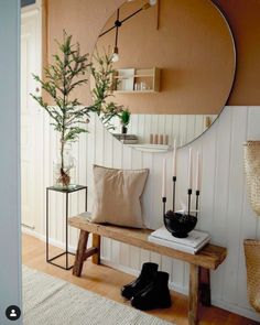 a wooden bench sitting in front of a round mirror on the side of a wall