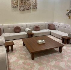 a living room filled with lots of white couches and wooden tables on top of carpeted flooring