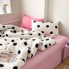 a bed with black and white polka dots on it, next to a pink pillow