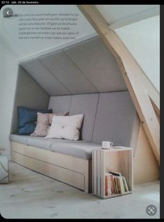 a couch in the corner of a room with some books and pillows on top of it