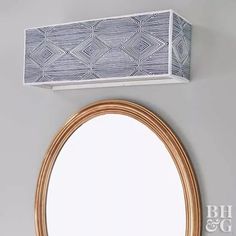 a round mirror sitting on top of a white wall next to a wooden framed mirror