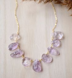 "Pale Purple Raw Amethyst Necklace Get in touch with your inner peace with Amethyst. Amethyst, the birthstone for February, is said to repel negative energies and promote calm. This necklace features natural, pale purple Amethyst crystals that have been semi-shaped into teardrops. Each stone is different in size and shape making every necklace a one of a kind. Choose to have it made in 14k gold filled or sterling silver.  GEMSTONE: Natural Amethyst STONE SIZE: Average 15-24mm (1\" and under) MET Gold Amethyst Necklace For Wedding, Wedding Gold Necklace With Amethyst, Delicate Crystal Gemstone Necklaces For Wedding, Delicate Crystal Gemstone Necklace For Wedding, Purple Gemstone Necklace For Wedding, Yellow Gold Amethyst Necklace For Wedding, Gold Gemstone Crystal Necklace For Wedding, Amethyst Necklace With Gemstone Accents For Wedding, Gold Crystal Gemstone Necklace For Wedding