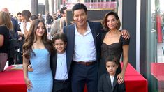 a man and two women standing next to a young boy on a red carpet