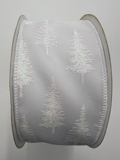 a white ribbon with trees on it is hanging from a wall in front of a gray background