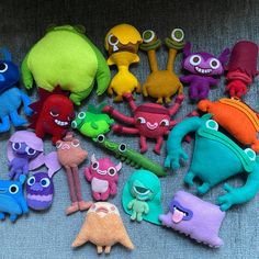 there are many different colored toys on the floor together, including one with eyes and arms