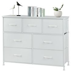 a white dresser with several drawers and a bird on top