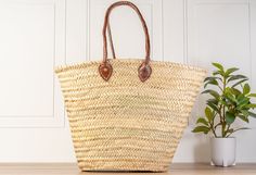 a large woven basket sitting on top of a wooden table next to a potted plant