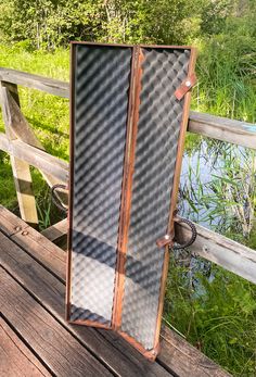 an open door sitting on top of a wooden deck next to a river and grass