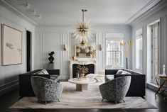 a living room filled with furniture and a chandelier hanging from the ceiling over a fire place