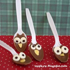 three spoons decorated like owls with googly eyes sitting on a red tablecloth