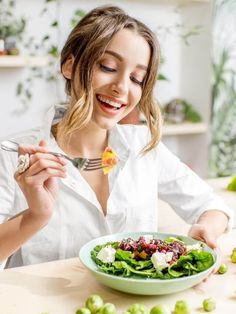 a woman sitting at a table with a plate of food in front of her and smiling