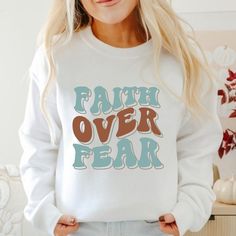 Embrace strength and faith with our 'Faith Over Fear' faith-based sweatshirt, a powerful reminder of courage and resilience in challenging times. Crafted from premium materials, this sweatshirt offers both comfort and style, featuring a timeless design that speaks volumes. Whether you're running errands or cozying up at home, let this sweatshirt inspire confidence and trust in God's plan. Perfect for gifting or personal wear, it's a meaningful addition to any wardrobe. Embody the message of fait Inspirational Letter Print Sweatshirt For Fall, Inspirational Slogan Sweatshirt For Fall, Inspirational Text Print Sweatshirt For Fall, Inspirational Text Print Fall Sweatshirt, Inspirational Streetwear Tops For Fall, Inspirational Graphic Print Sweatshirt For Fall, Inspirational Graphic Print Fall Sweatshirt, Fall Inspirational Graphic Print Sweatshirt, Challenging Times