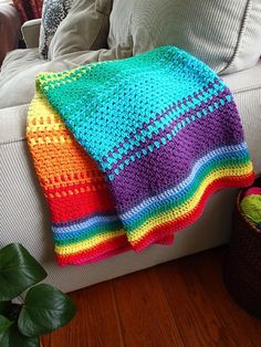 a crocheted blanket sitting on top of a couch next to a potted plant