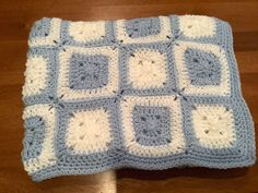 a blue and white crocheted blanket sitting on top of a wooden table